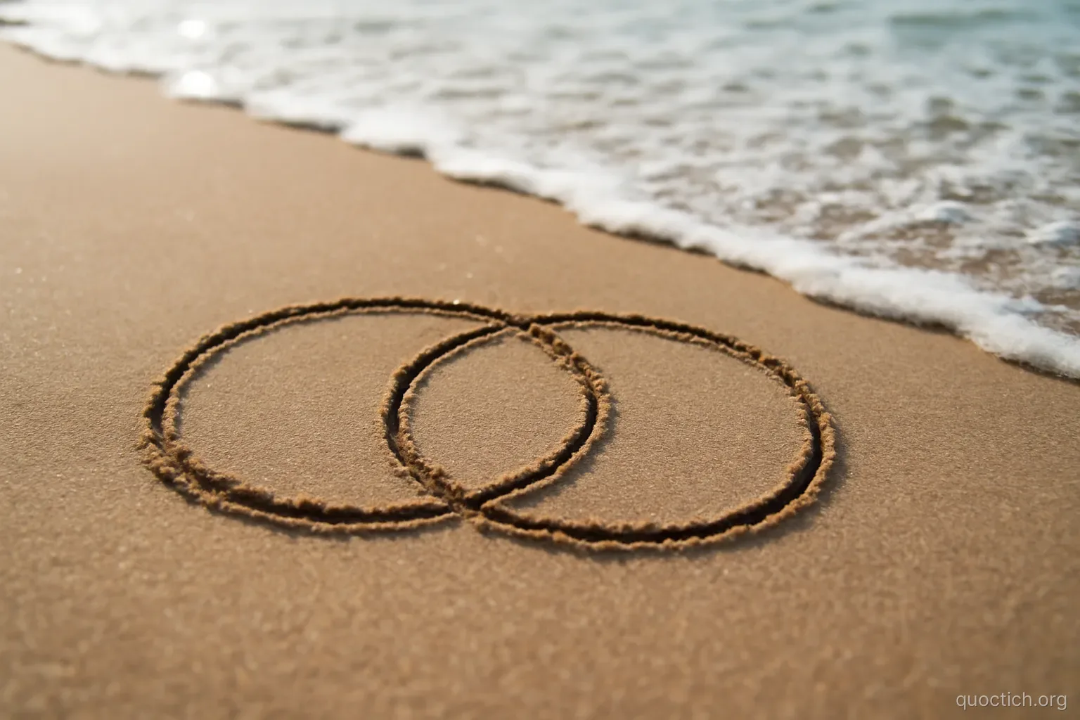 two overlapping circles drawn in wet sand on a beach with the tide approaching slowly