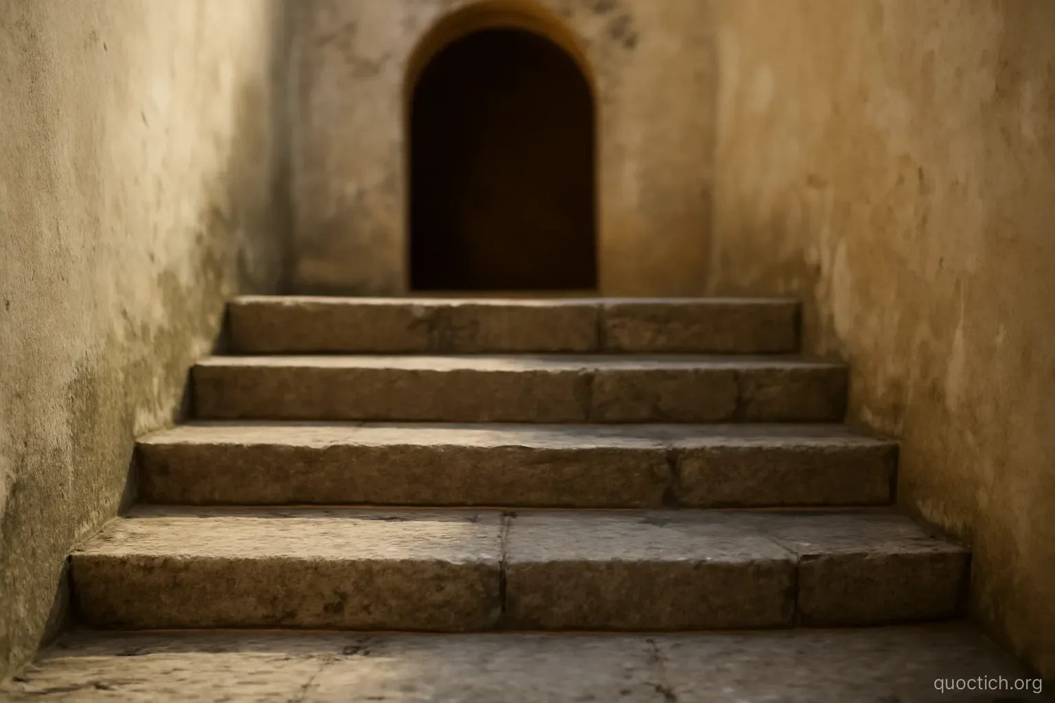five worn stone steps of different heights leading up to a plain arch, morning shade