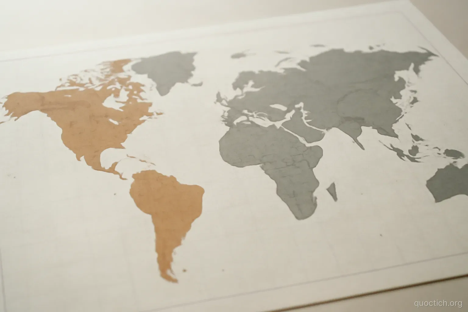 a world map printed on paper with two regions shaded in different tones, lying flat under even light